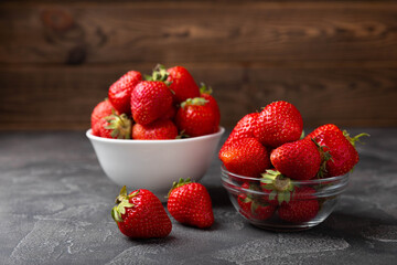 Fresh ripe strawberries in a plate on a black texture background.Vegetarian organic berry.Healthy food.Vitamins.Copy space.Place for text