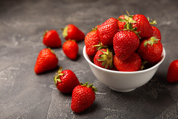 Fresh ripe strawberries in a plate on a black texture background.Vegetarian organic berry.Healthy food.Vitamins.Copy space.Place for text