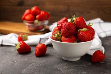 Fresh ripe strawberries in a plate on a black texture background.Vegetarian organic berry.Healthy food.Vitamins.Copy space.Place for text