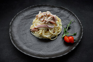 Pasta Carbonara with tomatoes, on a black plate