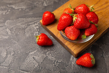 Fresh ripe strawberries in a plate on a black texture background.Vegetarian organic berry.Healthy food.Vitamins.Copy space.Place for text