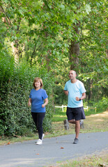 Old mature couple of man and woman running together in the city park to be fit and healthy