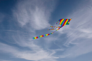 Colorful blue sky with white fluffy clouds and a flying colored kite