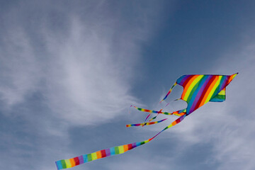 Obraz premium Colorful blue sky with white fluffy clouds and a flying colored kite