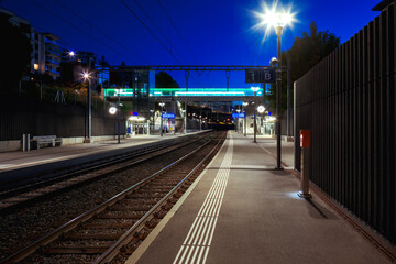 Fototapeta na wymiar Front view train station in switzerland at night with no people. Illuminate the scene of modern street lamps