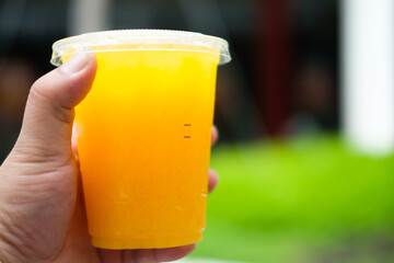 Man hand is holding juice against the nature background