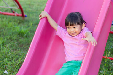 Portrait image of 4-5 yeas old baby. Happy Asian child girl smiling and laughing. She playing with slider bar toy at the playground. Learning and active of kids concept.
