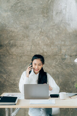 Asian businesswoman in formal suit in office happy and cheerful during using smartphone and working