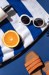 Summer vacation beach concept  with retro sunglasses, striped towel and flip flops on the blue...