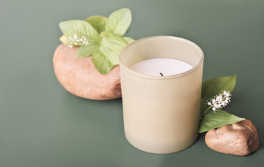 soy wax candle with herbal feen scent. home scents and romantic fragrances for house. natural stone decor and plants on green background.