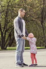 Dad plays with his daughters in the park. Twirling a girl around. Family