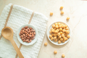 Wood spoon, beans,  chickpeas in white plates, kitchen towel, on a kitchen top 