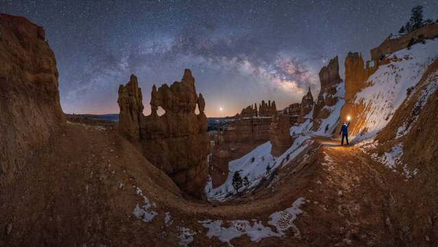 Anonymous traveler standing on snowy mountain with milky way on sky