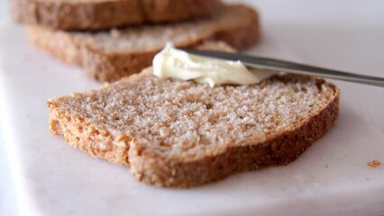 Spreading butter on whole grain yeast-free gluten-free bread close-up. Healthy breakfast