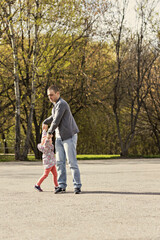 Dad is playing with his daughter in the backyard. Unwinds it around itself. Family, dad plays with his daughter on weekends