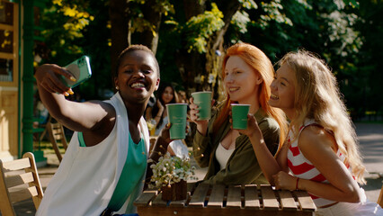 Selfie time for a group of amazing multiracial good looking ladies while sitting at the cafe in the...