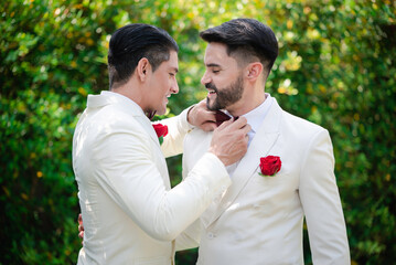 gay bride and groom wearing  white suit with red rose in the pocket in LGBT gay wedding ceremony,romantic, selective focus.