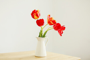 Elegant flowers in a vase background. Interior with a bouquet of red tulips. Minimalistic scandi style. Atmosphere of comfort and simplicity