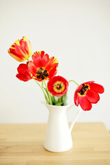 Elegant flowers in a vase background. Interior with a bouquet of red tulips. Minimalistic scandi style. Atmosphere of comfort and simplicity
