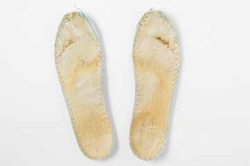 Dirty old shoe insoles. White background.
