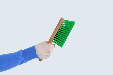 Green brush for cleaning with a wooden handle in the hand of  caucasian woman. White isolate.