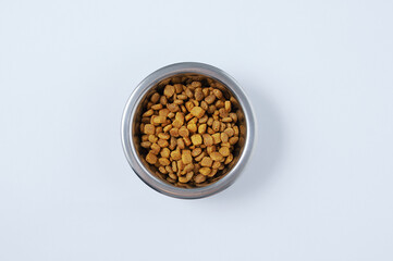 Metal bowl with dry cat food on  white background.
