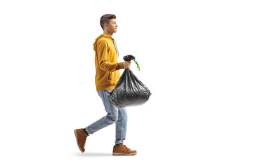 Full length profile shot of a casual guy carrying a plastic waste bag