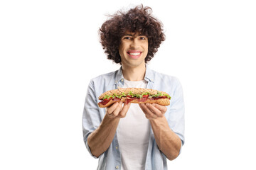 Young man with curly hair holding a baguette sandwich and smiling