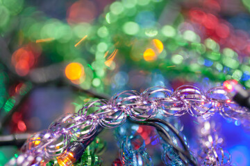 Macro of the purple tinsel on the another colorful tinsel and garland background. Christmas and New year background