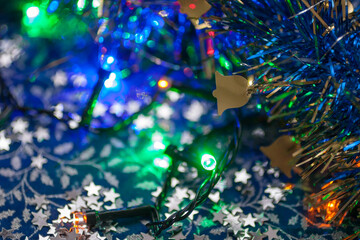 Macro of the blue Christmas tinsel with the golden bell, colorful garland on the blue and silver...