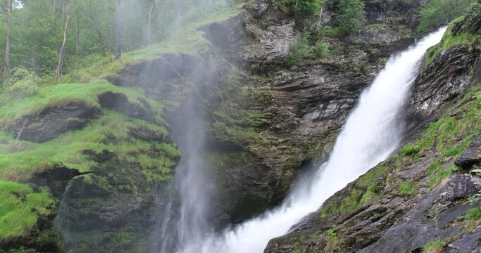 Wonderful landscapes in Norway. Vestland. Beautiful scenery of Svandalsfossen waterfall on the Saudafjorden fjord. Mountains and trees on rocks in background. Rain 4K UHD 59,94fps ProRes 422 HQ 10 bit