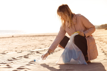 Woman assistant, activist cleaning sandy beach near ocean from plastic waste, garbage. Eco tourism, ocean pollution