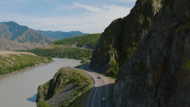 Mountains valley of Altai with traffic cars on Chuya highway and Katun river, Siberia, Russia. Beautiful summer nature landscape at during daytime. Aerial view from a drone