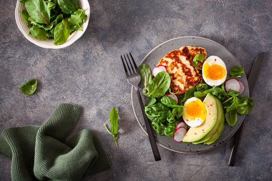 healthy keto paleo diet breakfast: boiled egg, avocado, halloumi cheese, salad leaves
