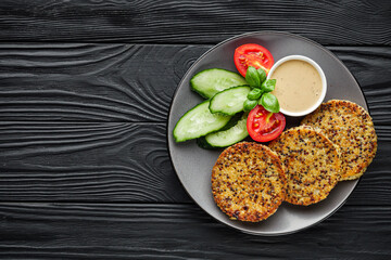 quinoa cutlet with vegetables on a black wooden rustic background