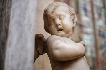 Fototapeta na wymiar Baby angle with wings crying sculpture in the church