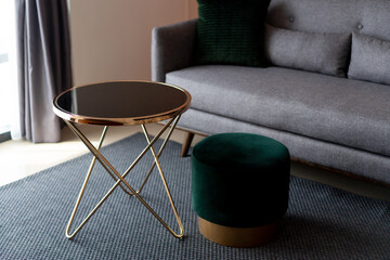 Unique gold colour coffee table with green chair and grey sofa