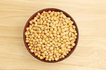 soybean in a bowl on wooden background, top view, flat lay, top-down, selective focus.
