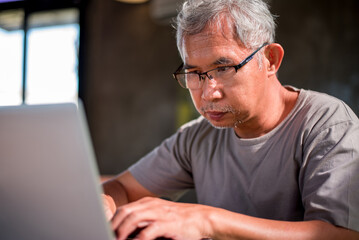 Asian senior man using laptop to do business in the home