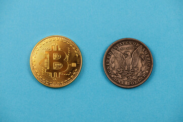 Gold bitcoin coin and one dollar silver coin on blue background isolated