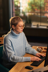 Vertical Screen: Young Attractive Woman Using Desktop Computer in Stylish Loft Apartment During the Day. Creative Female Checking Social Media, Browsing Internet, Wearing Cozy Clothes.