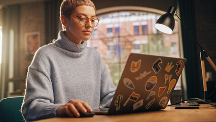 Young Beautiful Woman Working from Home on Laptop Computer with Stickers in Sunny Stylish Loft...