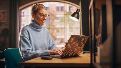 Young Attractive Woman Working from Home on Laptop Computer with Stickers in Sunny Stylish Loft...