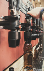 bartender hand at beer tap pouring a draught beer in bottle in tap room