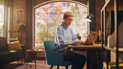 Young Diverse Woman Working from Home on Laptop Computer with Stickers in Sunny Stylish Loft...