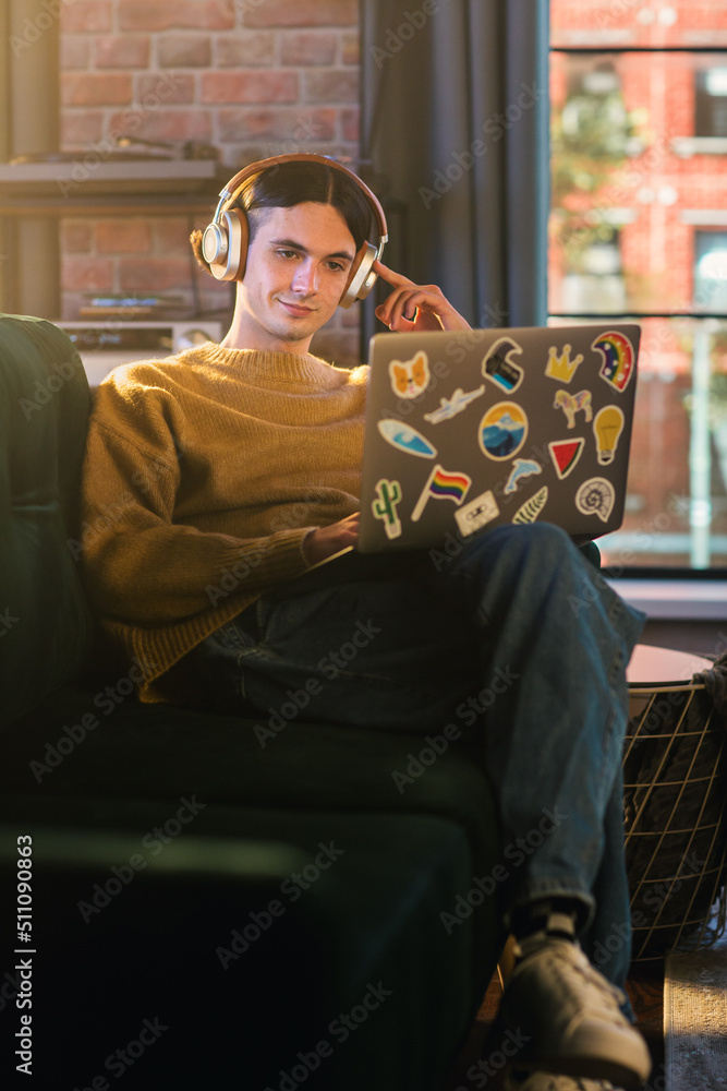 Poster vertical screen: young handsome man working from home on laptop computer in stylish loft apartment d