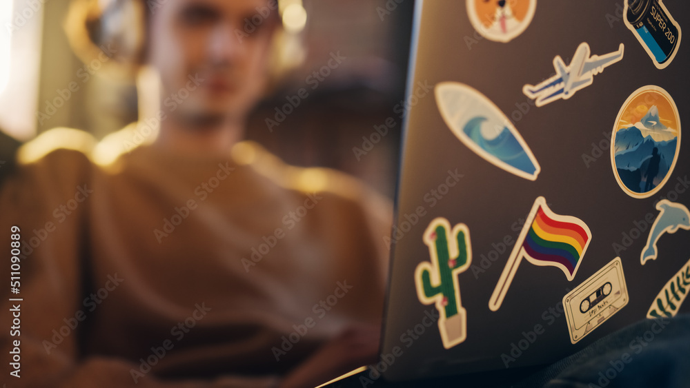Poster close up footage of person using laptop computer with diverse lgbt and lifestyle stickers on the bac