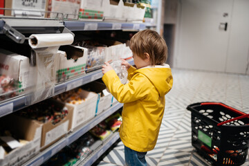 child in the market with a grocery cart, puts sweets in a bag. Shopping Day