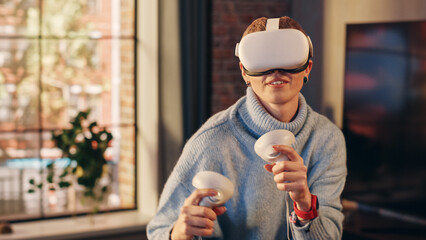 Young Female Gamer with Short Hair Having Fun and Playing Virtual Reality Game at Home in Her Living Room. She is Wearing a Modern Headset and Using Controllers. Stylish Apartment with Big Window.