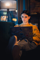 Vertical Screen: Young Handsome Man Working from Home on Laptop Computer in Stylish Loft Apartment in the Evening. Creative Person Checking Social Media, Browsing Internet.